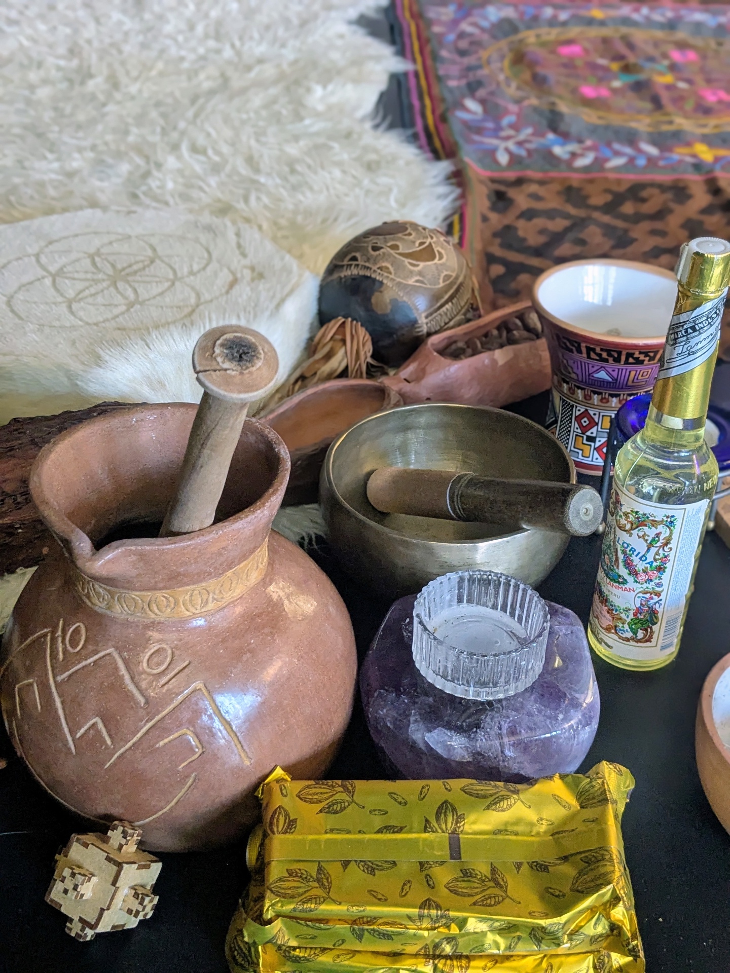 Close-up of cacao ceremony tools — clay jug, singing bowl, amethyst and cacao bars